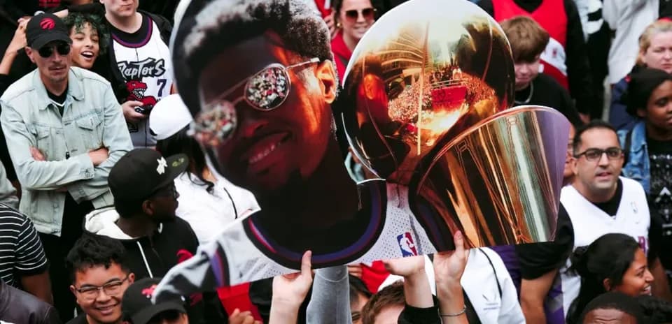 Supporters holding a large cutout and trophy
