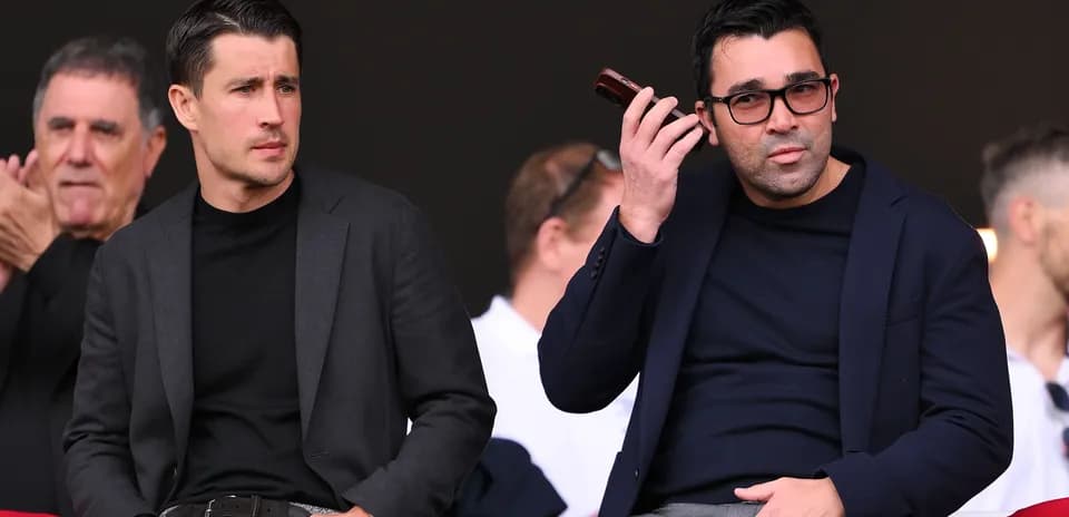 Deux hommes assis dans les tribunes, observant le match
