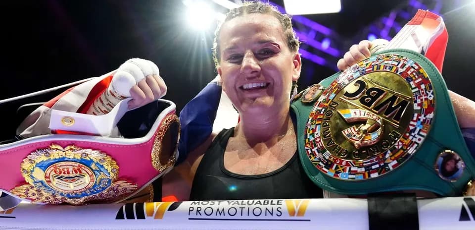 Boxeuse souriante tenant des ceintures de championne