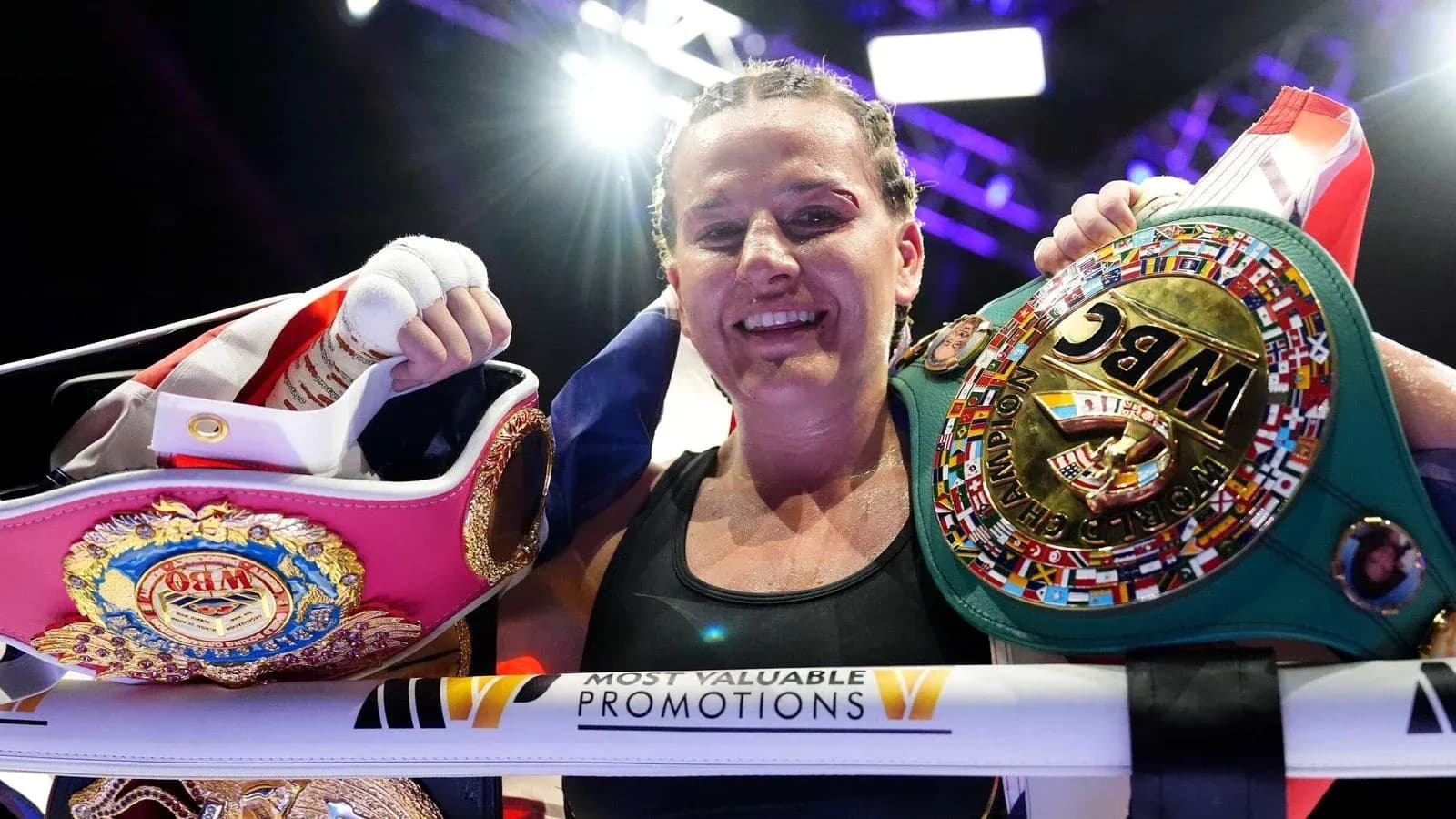 Boxeuse souriante tenant des ceintures de championne