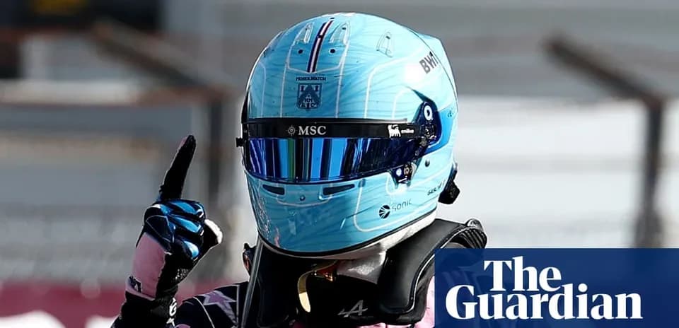 Pilote de Formule 1 avec un casque bleu levant un doigt