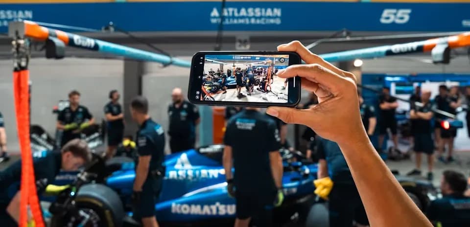 Person filming Williams Racing team in garage