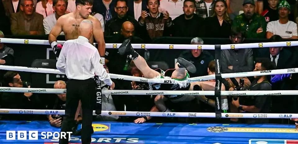 Boxer knocked out with legs over ropes in ring