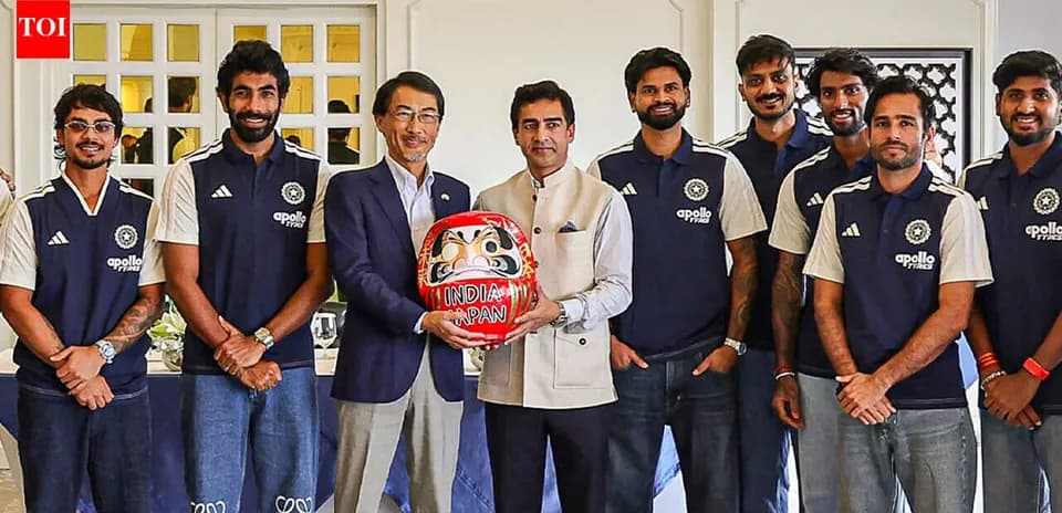 Équipe de cricket posant avec un Daruma