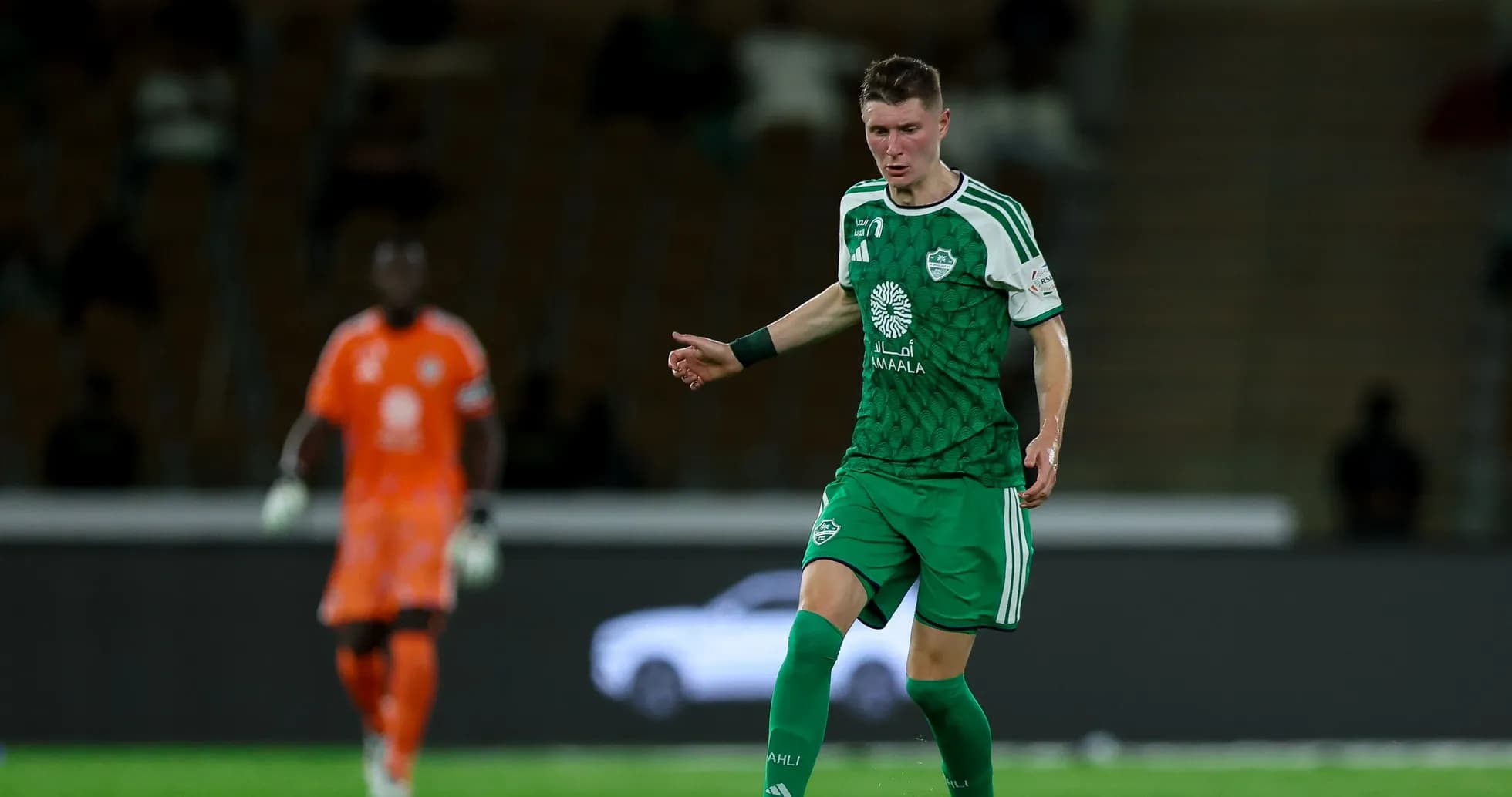 Joueur en vert dribbles sur le terrain de football