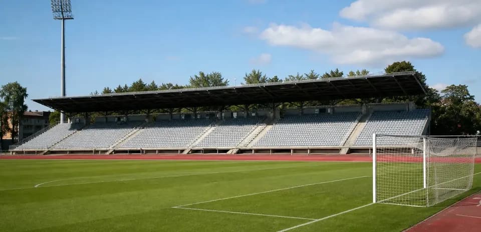 Stade de football avec tribunes et terrain vert