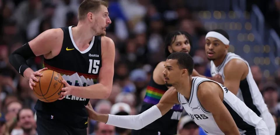 Joueur de Denver dribblant sous la pression d'un adversaire