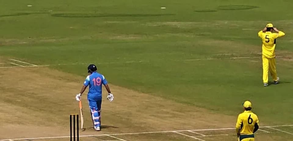 Batsman in blue uniform walking towards the pitch