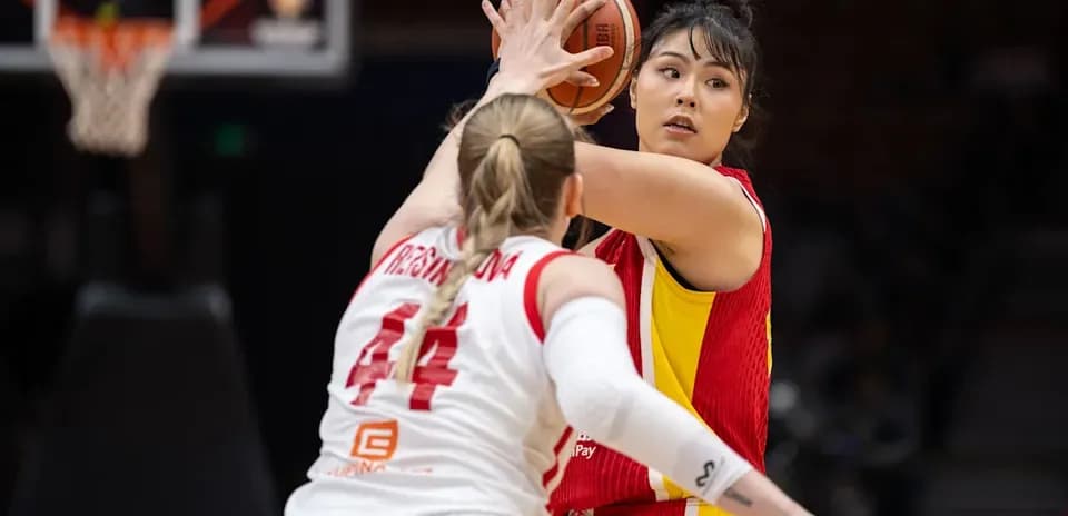 Joueuse en rouge dribblant sous la pression d'une défenseuse