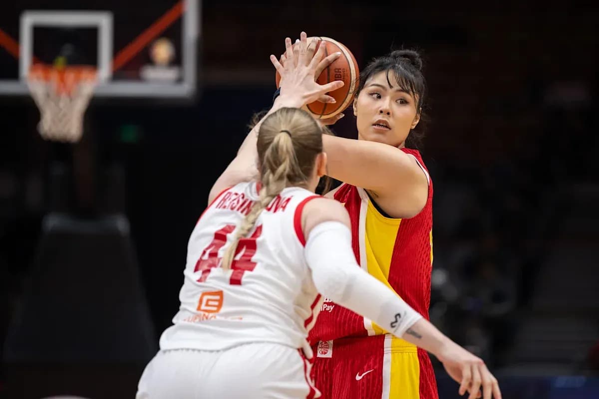 Joueuse en rouge dribblant sous la pression d'une défenseuse