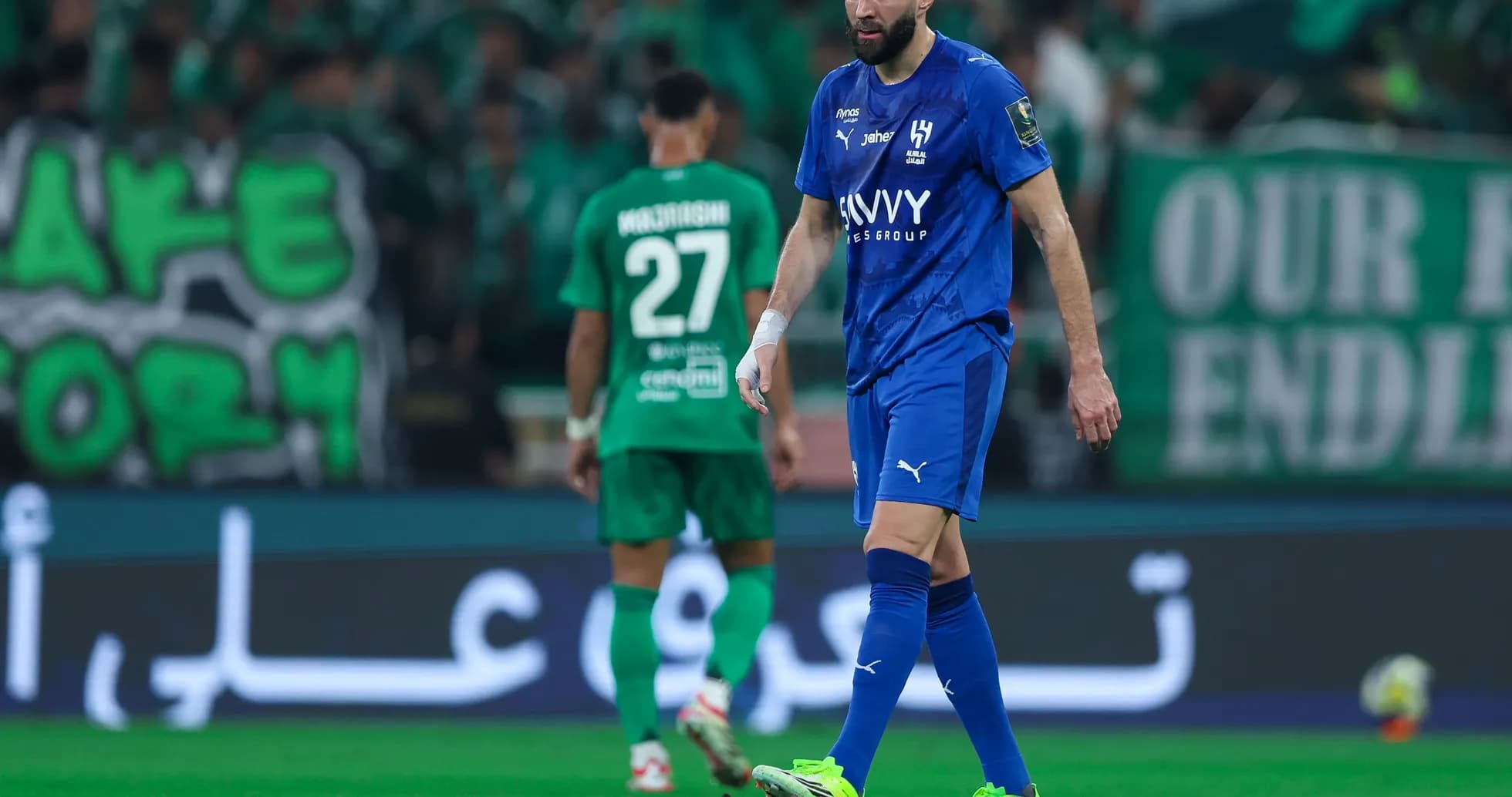Joueur en maillot bleu marchant sur le terrain de football
