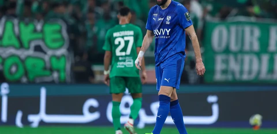 Joueur en maillot bleu marchant sur le terrain de football