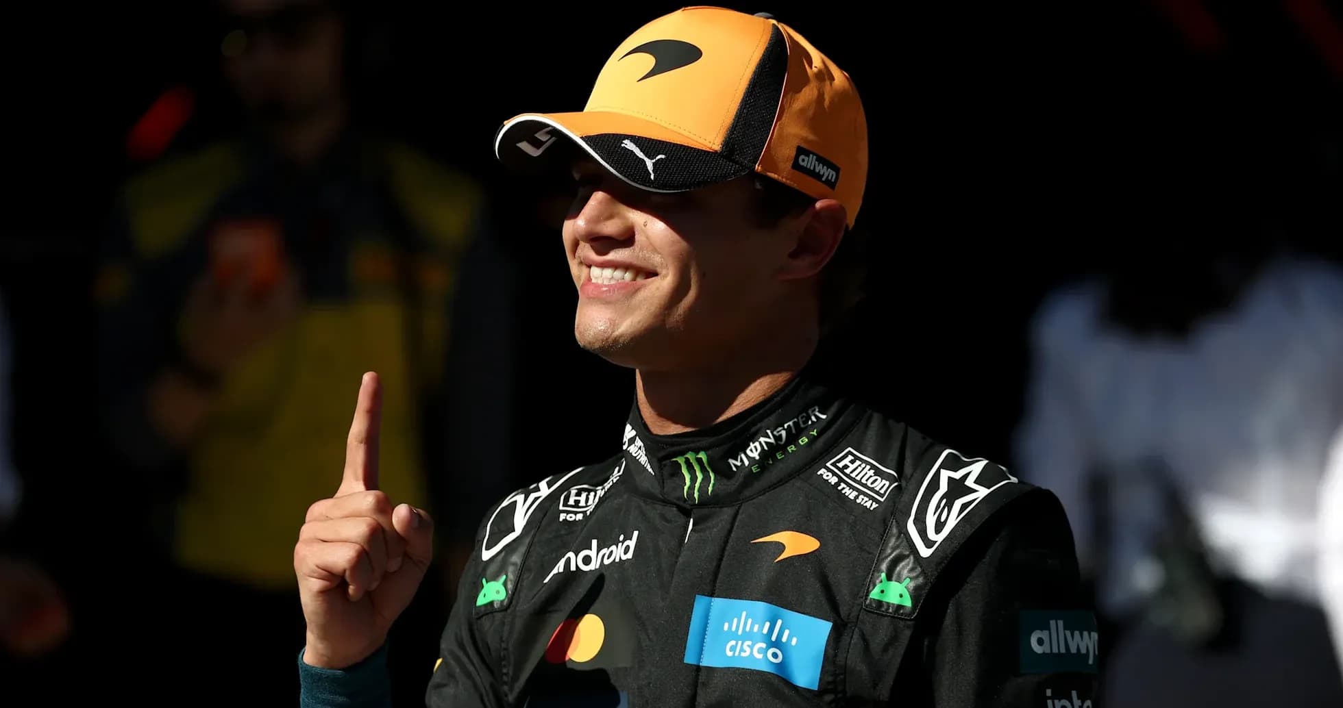 Pilote de F1 avec un chapeau McLaren montrant un doigt