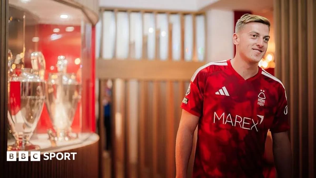 Joueur de Nottingham Forest en maillot rouge près des trophées