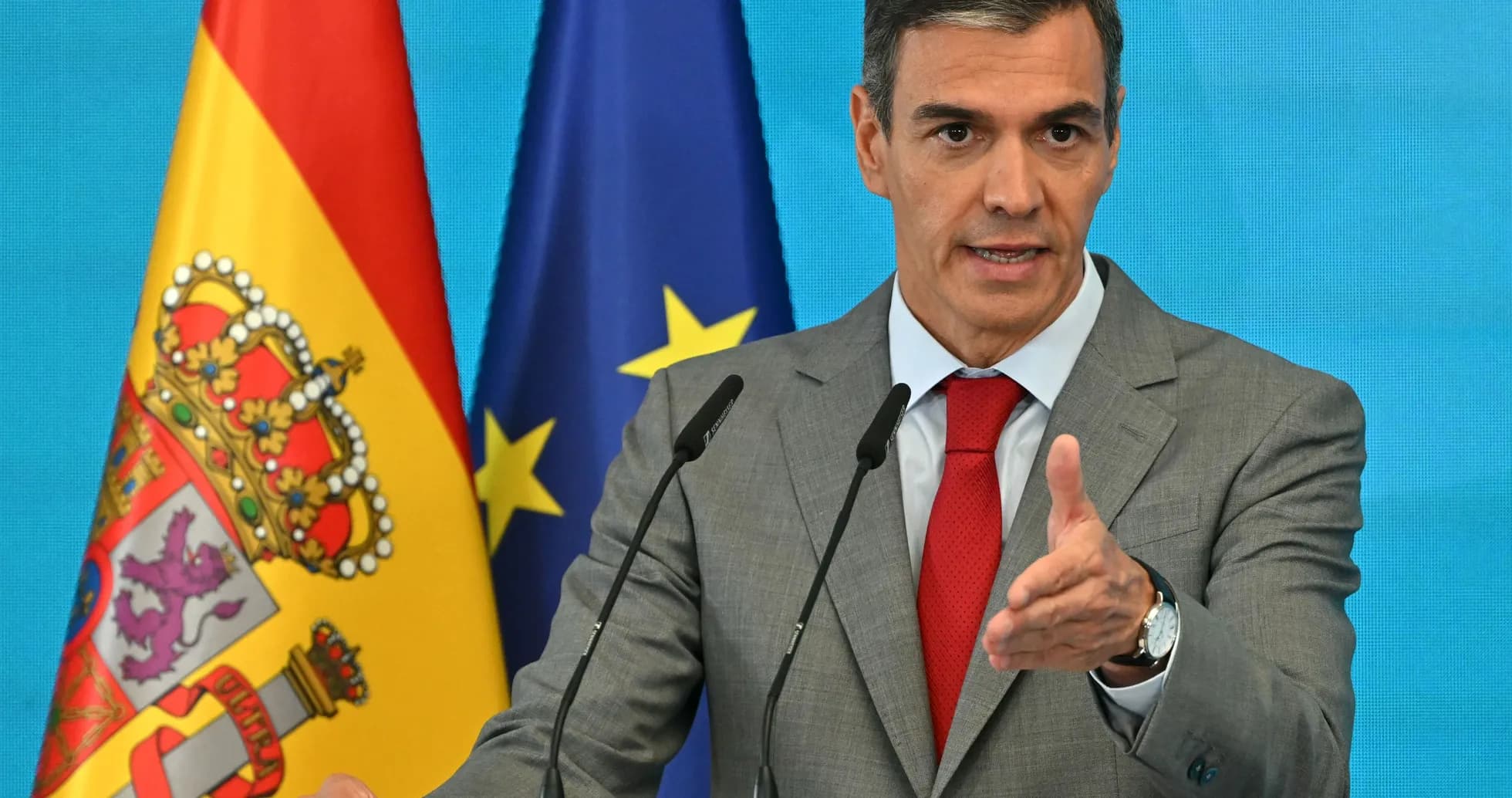 Homme parlant à un podium avec drapeaux espagnol et européen