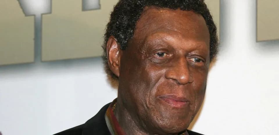 Homme souriant avec cheveux bouclés en arrière-plan neutre