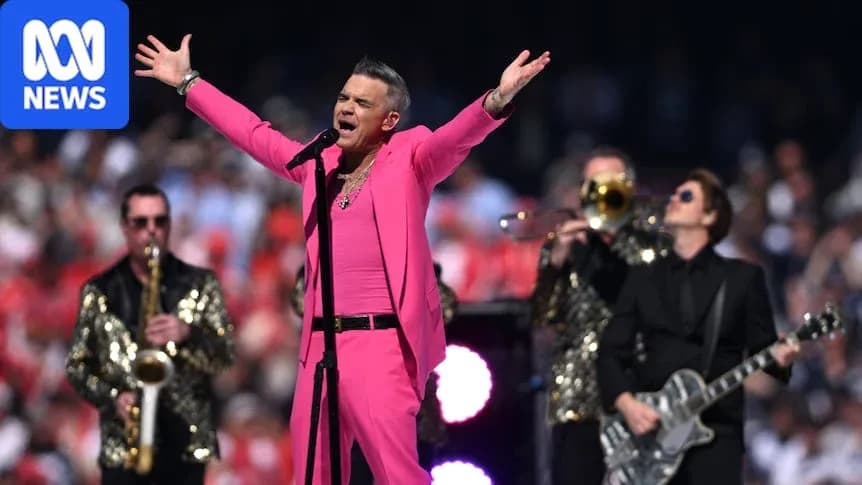 Robbie Williams performing in pink outfit with band