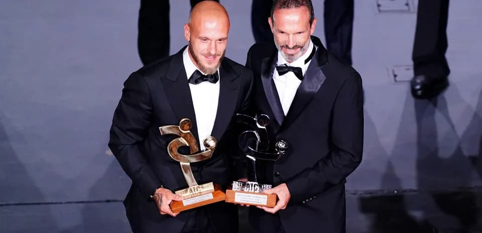 Deux hommes en costume tenant des trophées lors d'une cérémonie