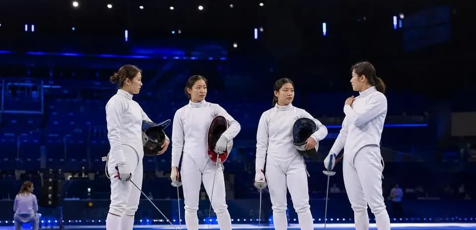 Quatre escrimeuses discutant sur le terrain d'entraînement