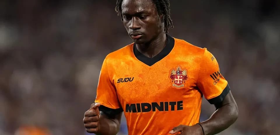 Joueur en maillot orange marchant sur le terrain