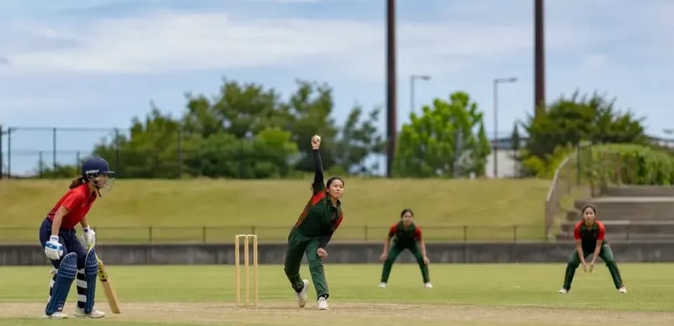 Joueuse lançant la balle pendant un match de cricket