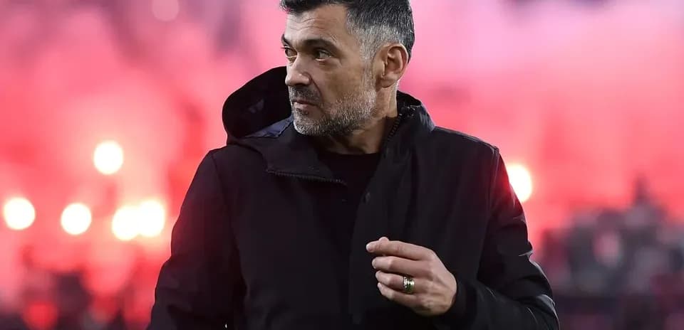Entraîneur observant le match avec fumigènes en arrière-plan