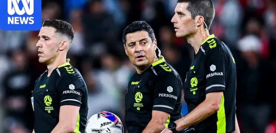 Trois arbitres discutant pendant un match de football