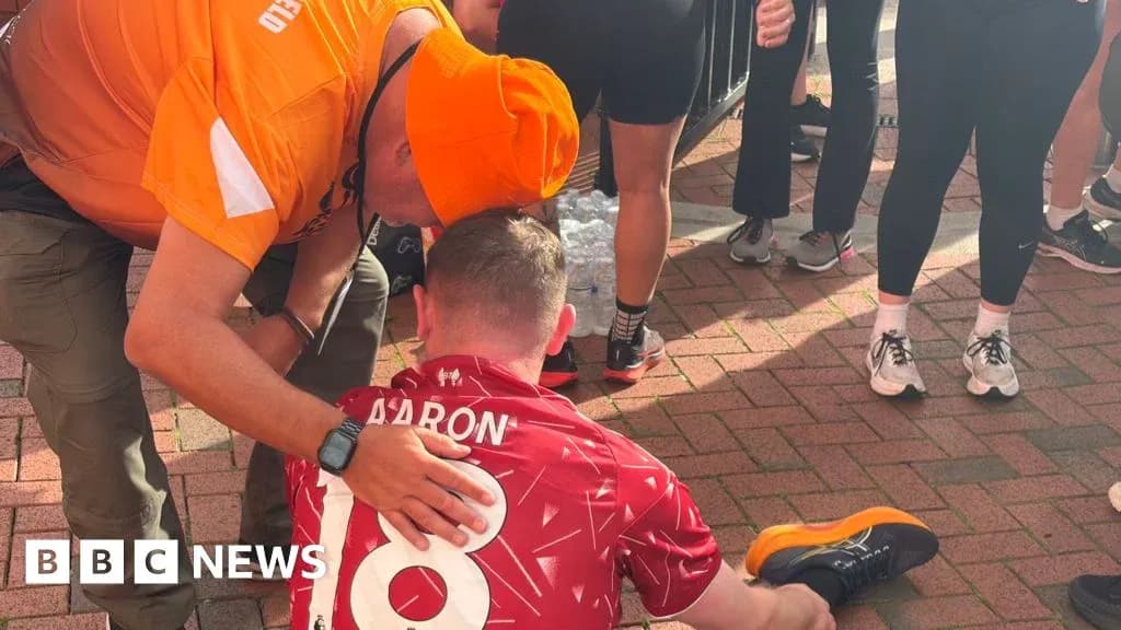 Un coureur assis, aidé par un homme en orange Un coureur assis, aidé par un homme en orange