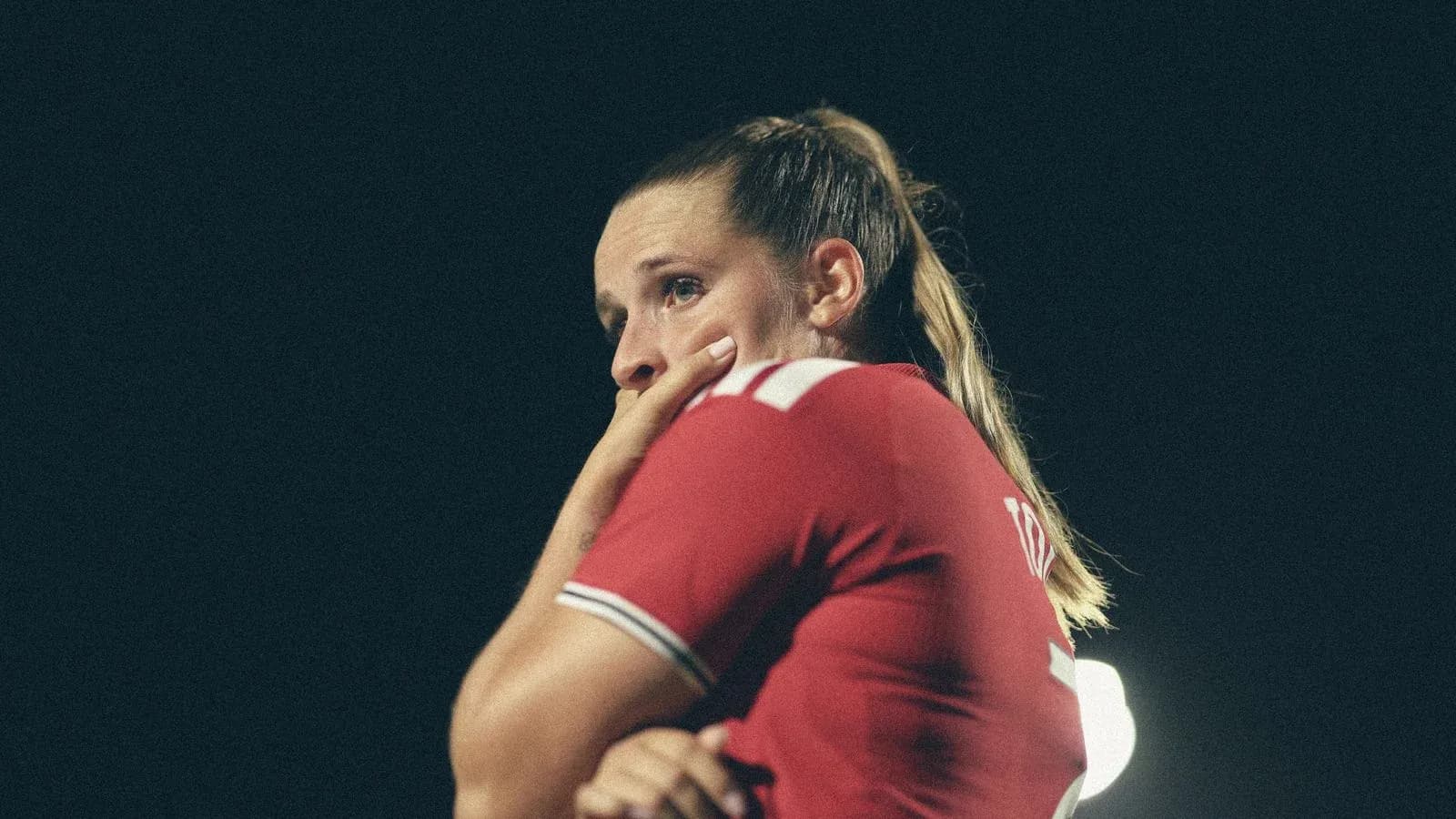 Joueuse en maillot rouge, pensive sur le terrain Joueuse en maillot rouge, pensive sur le terrain