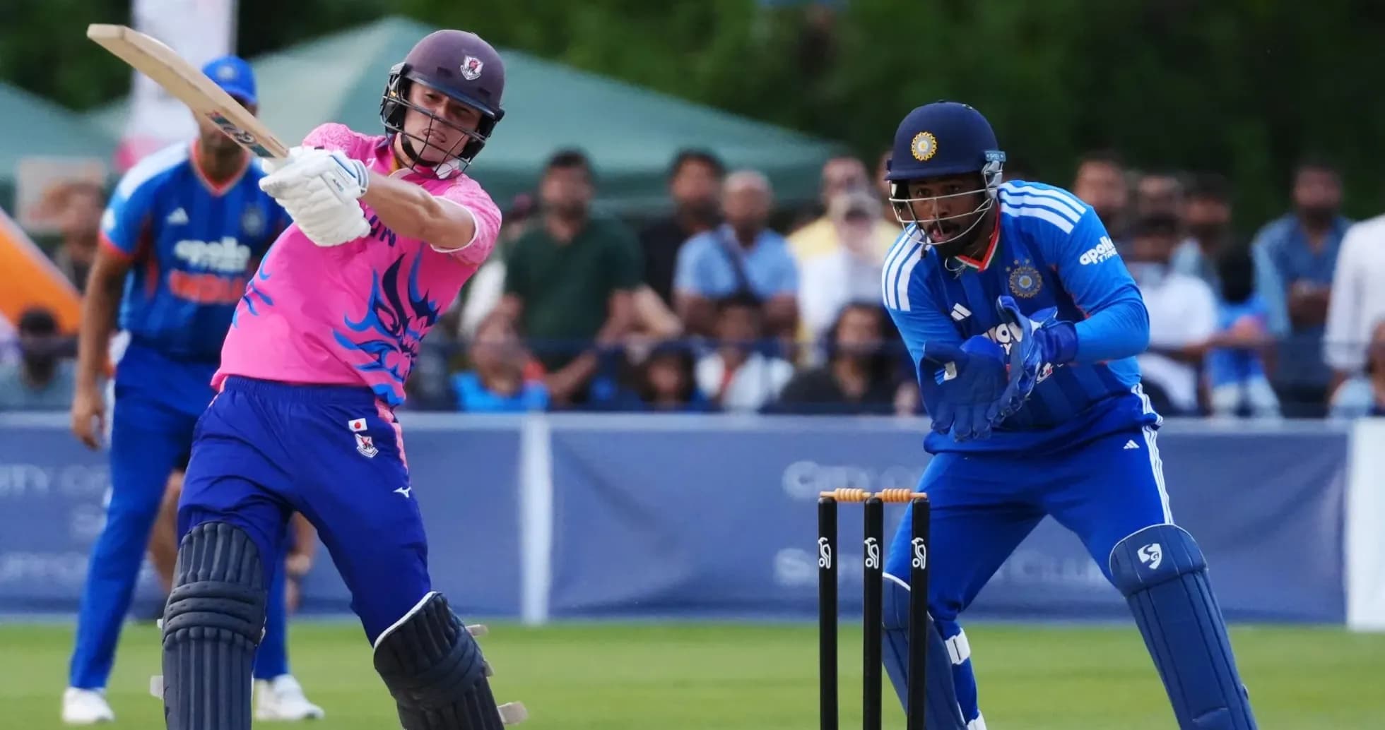 Batsman hitting ball while wicketkeeper prepares to catch Batsman hitting ball while wicketkeeper prepares to catch