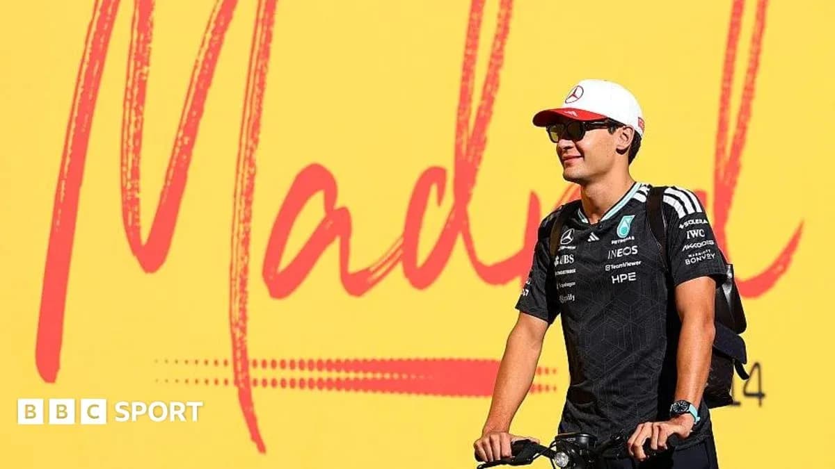 Pilote de Formule 1 sur un vélo devant une affiche Pilote de Formule 1 sur un vélo devant une affiche