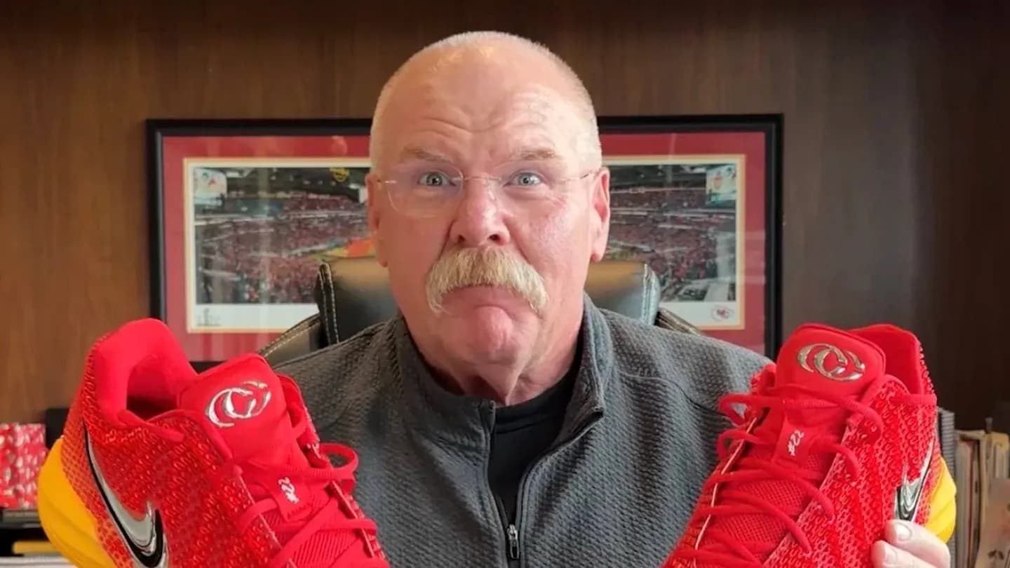 Person holding red sports shoes in office setting Person holding red sports shoes in office setting