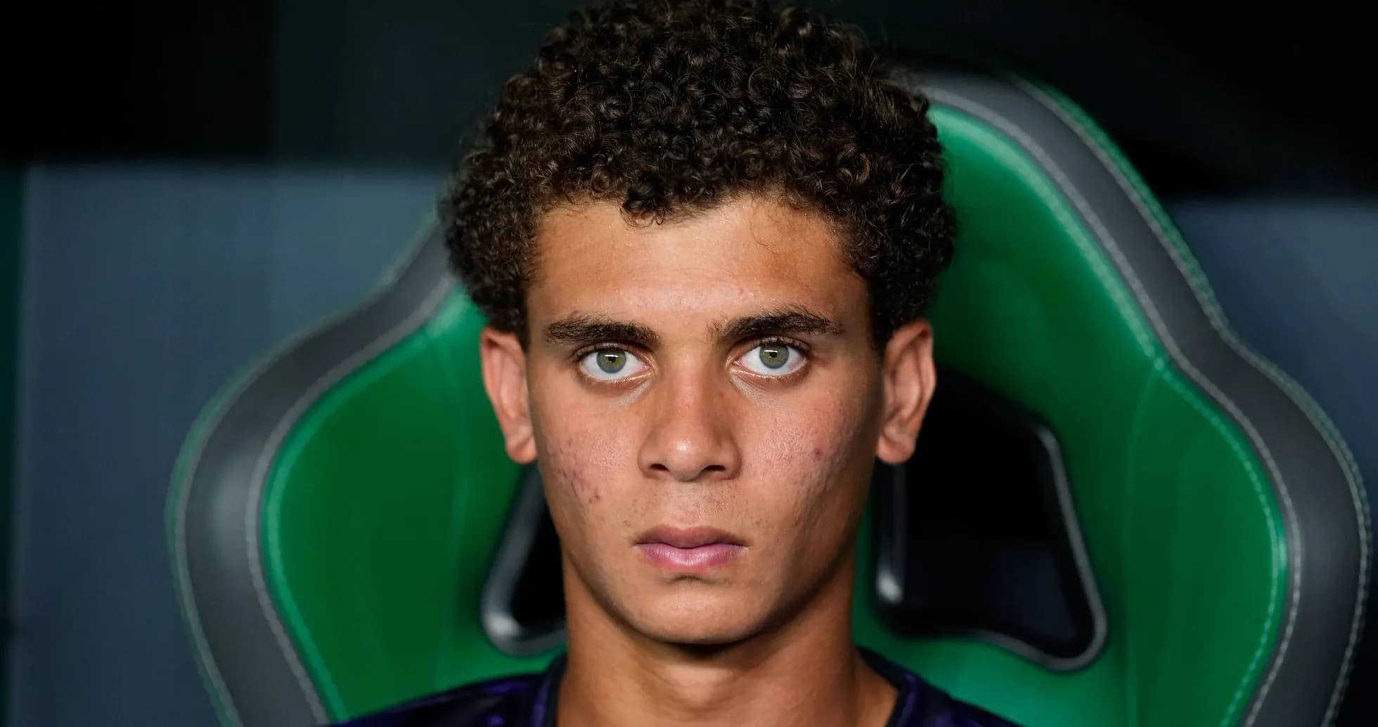 Jeune joueur assis sur un fauteuil vert Jeune joueur assis sur un fauteuil vert